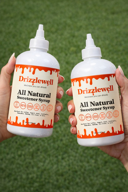 Two bottles of Drizzlewell All Natural Sweetener Syrup held outdoors, highlighting the portable squeeze bottle design. This zero sugar, keto-friendly syrup is made with Allulose and Monk Fruit, perfect for sweetening coffee, yogurt, and lattes on the go.
